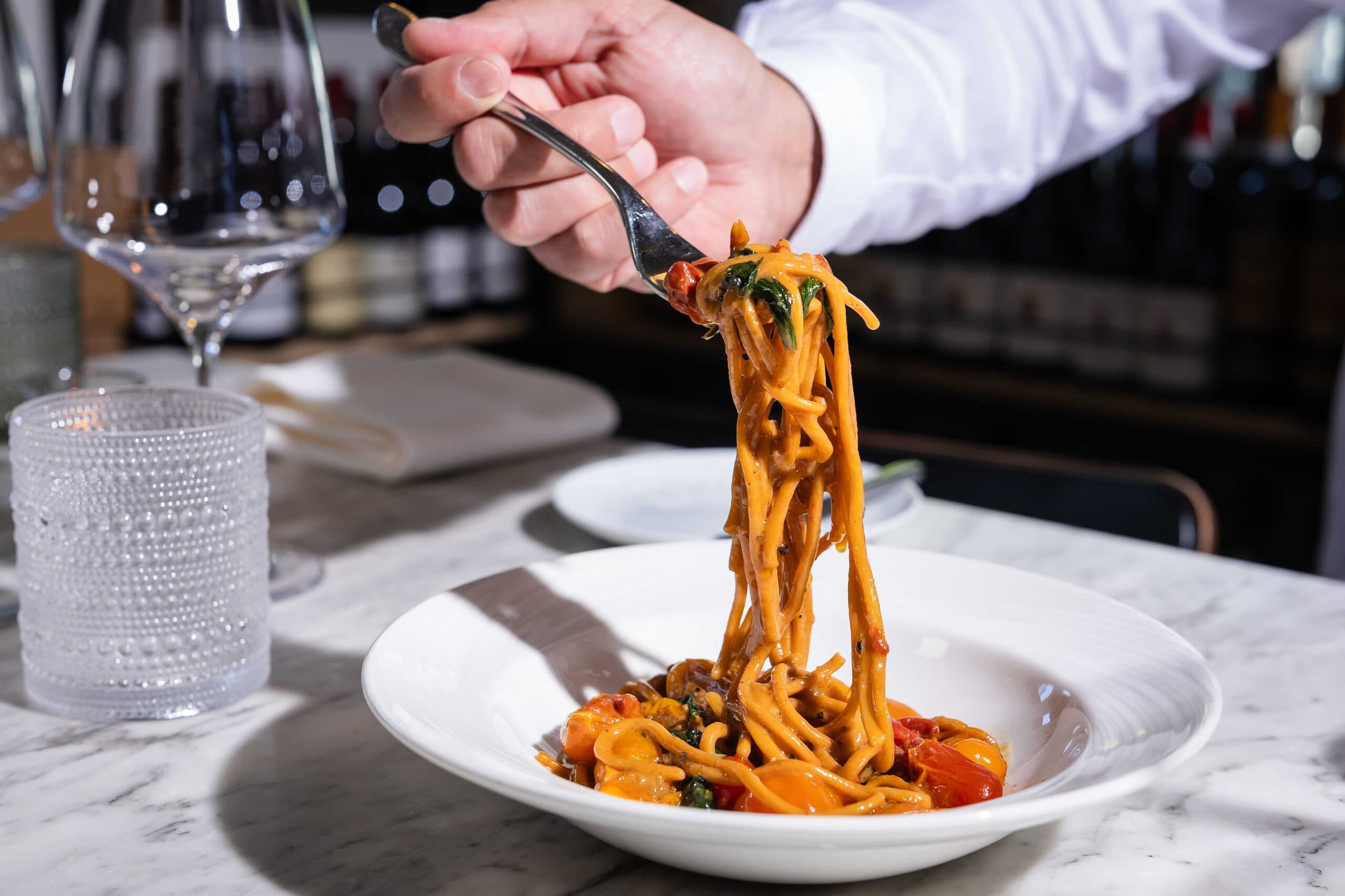 A forkful of spaghetti lifted from a bowl at the bar